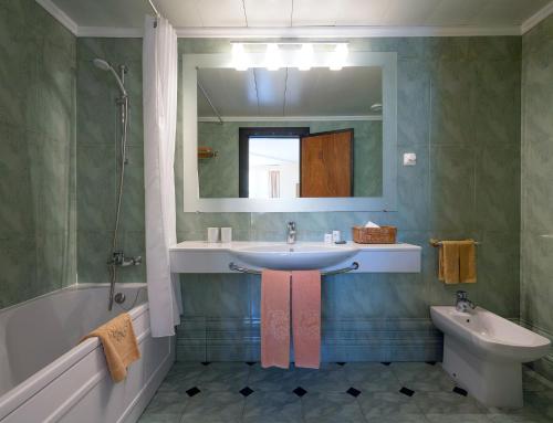 a bathroom with a sink and a mirror and a toilet at Dom Pedro Madeira in Machico