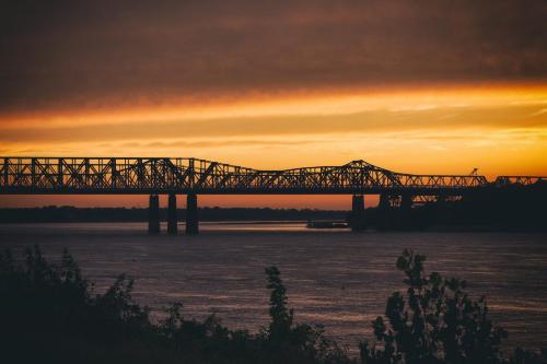 a train bridge over the water at sunset at Hu Hotel Memphis in Memphis