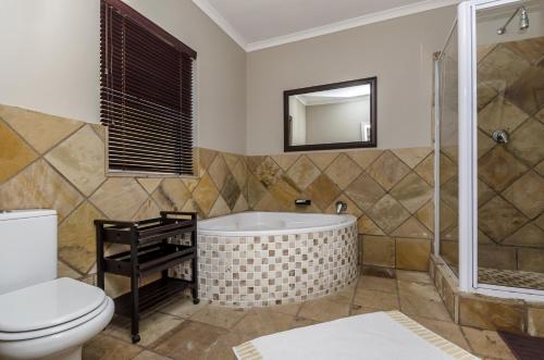 a bathroom with a tub and a toilet at Abalone Guest House in Port Elizabeth