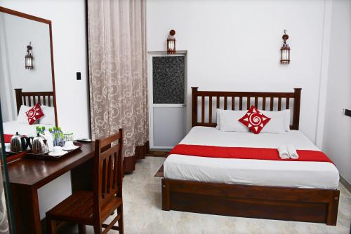 a bedroom with a bed and a desk and a mirror at Sea View Tourist Inn in Tangalle