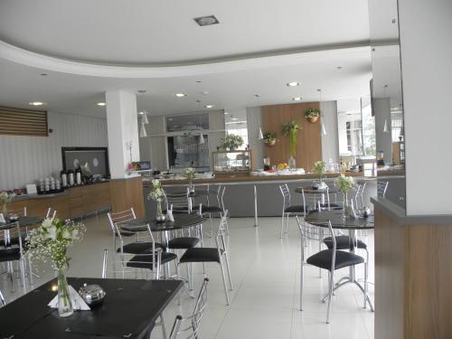 a dining room with tables and chairs and a kitchen at Benos Hotel in Santa Rosa