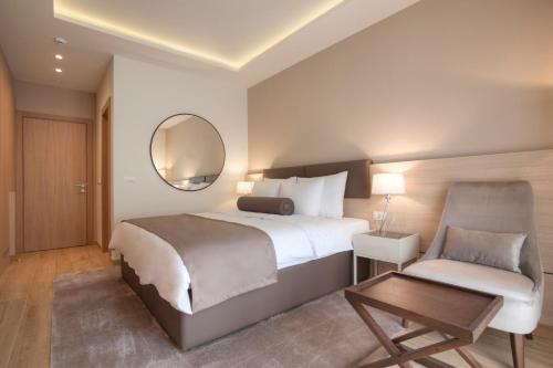 a bedroom with a bed and a chair and a mirror at Hotel Villa Gracia in Budva