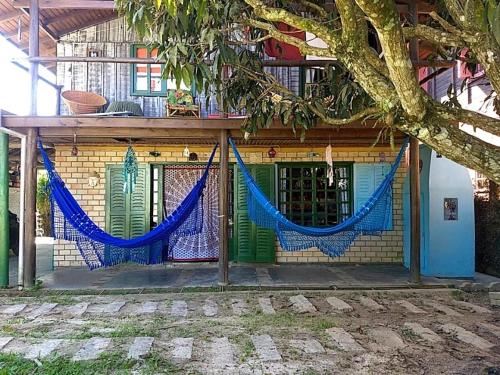 a building with a fence with blue hammocks in front of it at CasaHostel Floresce in Praia do Rosa