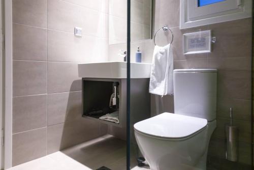 La salle de bains est pourvue de toilettes blanches et d'un lavabo. dans l'établissement TONI'S Lovely Retreat Studio for couples in Centre, à Athènes