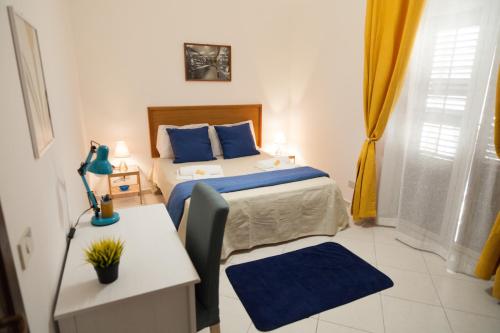Schlafzimmer mit einem Bett mit blauen Kissen und einem Tisch in der Unterkunft Casa Benzo in Palermo