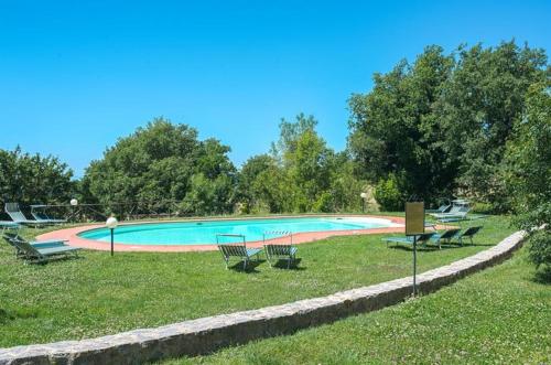 a swimming pool with chairs in the grass at Mela a Poderone in Roccalbegna