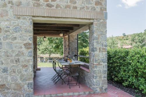 a stone building with a table and chairs on a patio at Mela a Poderone in Roccalbegna