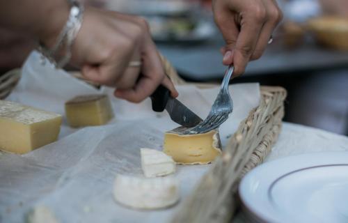 a person cutting cheese with a fork and knife at L'Enclos des Lauriers Roses in Cabrières