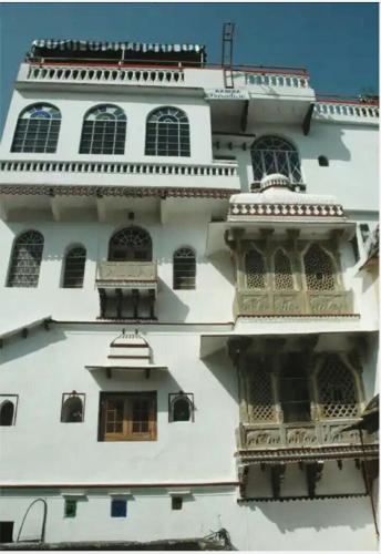 a tall white building with windows and balconies at Kasera Paradise in Būndi