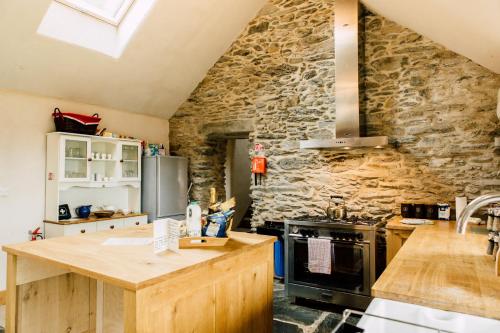 a kitchen with a stone wall and a stove at Glyn Mawr Barn in Bala