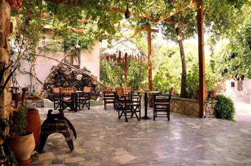 an outdoor patio with tables and chairs and trees at Hotel Sofia in Matala