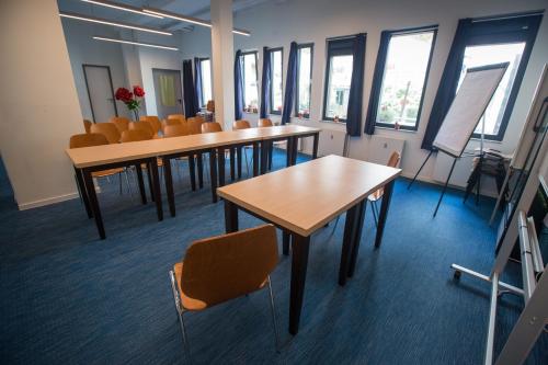 a row of tables and chairs in a room with windows at acama Hotel & Hostel Kreuzberg in Berlin