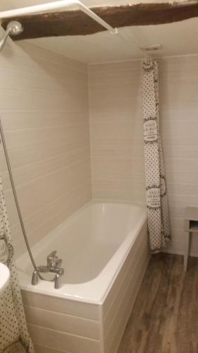 La salle de bains est pourvue d'une baignoire et d'un rideau de douche. dans l'établissement Logis Gascons Gite 1, à Saint-Justin