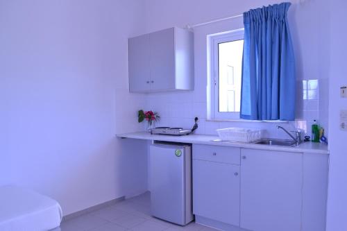 a white kitchen with a sink and a window at Asteri apartments in Malia