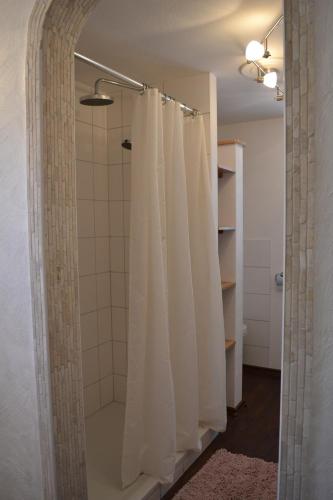 a bathroom with a shower with white shower curtain at Ferienhaus Pfistermühle in Wissembourg