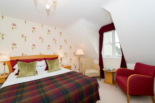 a bedroom with a bed and a red chair at Three Ways House Hotel in Chipping Campden