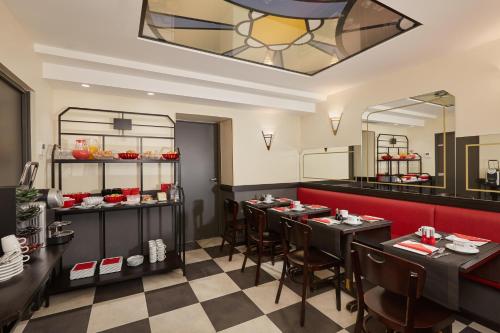 un ristorante con tavoli e sedie neri e uno specchio di Hôtel Raspail Montparnasse a Parigi