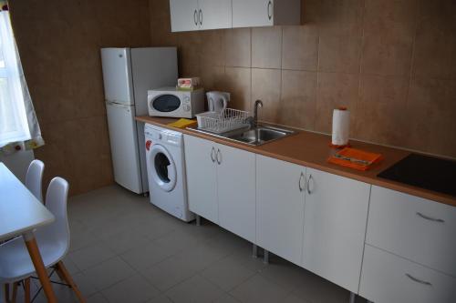 a kitchen with a sink and a refrigerator and a washing machine at Casa da Guida in Lajes das Flores