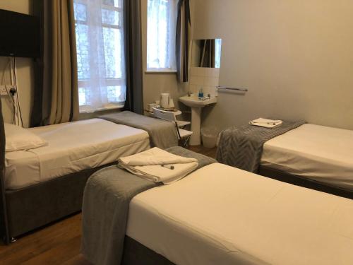 a hotel room with three beds and a sink at The Crystal Lodge Hotel in Croydon