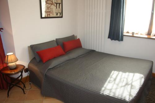 ein Bett mit zwei roten Kissen in einem Schlafzimmer in der Unterkunft Au pied des Alpes in Vaulnaveys-le-Haut