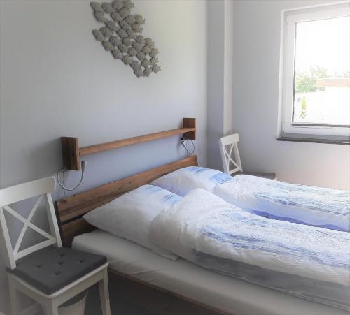 2 Betten in einem Schlafzimmer mit einem Stuhl und einem Fenster in der Unterkunft Ferienhaus Brückenblick 12 a in Fehmarnsund