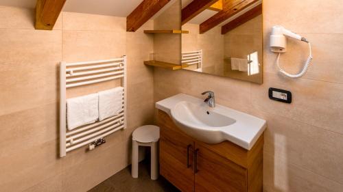 a bathroom with a sink and a mirror and a stool at Villa Hilde in San Cassiano