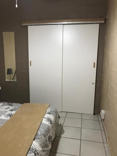 a bedroom with two white cabinets and a bed at Ian and Pam's Flatlet in Empangeni