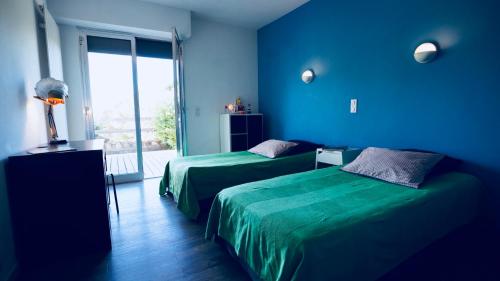 Cette chambre bleue comprend 2 lits et une fenêtre. dans l'établissement Golfe de Saint Tropez- Beauvallon Villa, à Grimaud