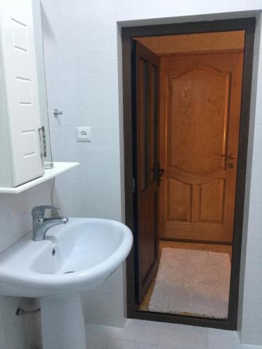 a bathroom with a sink and a wooden door at Teona's Guesthouse in Mestia in Mestia