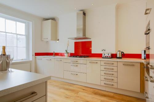 una cocina con armarios blancos y encimeras rojas en Sea View Penthouse Maisonette, en Brighton & Hove