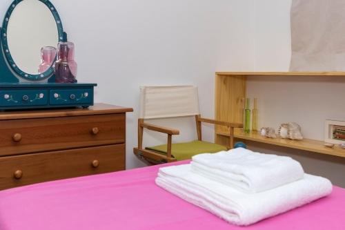 ein Schlafzimmer mit einem Bett mit einem Spiegel und einem Stuhl in der Unterkunft Casa Caió in Ribeira Grande