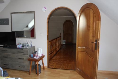 an arched wooden door in a room with a staircase at Chambre en Ardenne in Graide