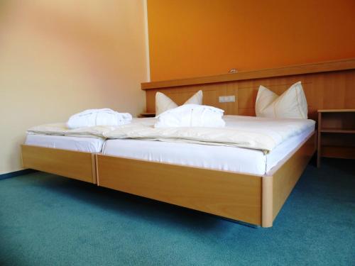 a bedroom with a bed with white sheets and pillows at Hotel & Restaurant Zur Weintraube in Jena