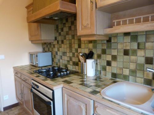 a kitchen with a sink and a stove top oven at Jolie maison de campagne in Lainsecq