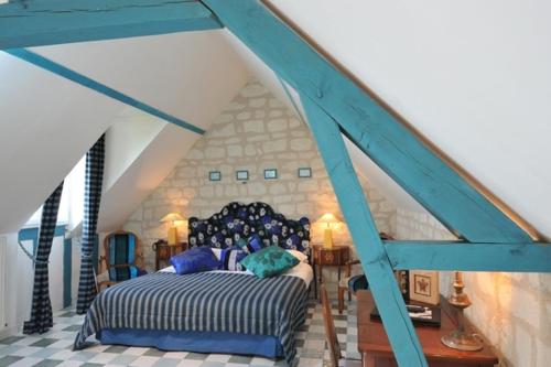 a bedroom with a blue bed in a room at Logis Demeure de la Vignole in Turquant