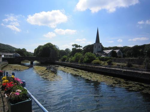 a river with a bridge and a church in the background at The Lookout, Glenarm in Glenarm