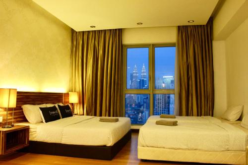 Cette chambre comprend deux lits et une grande fenêtre. dans l'établissement T1 KLCC view Studio@Regalia Infinity Pool, à Kuala Lumpur