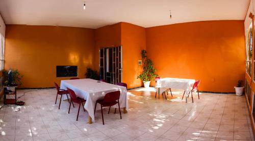a room with two tables and chairs and orange walls at Le k in Nouakchott
