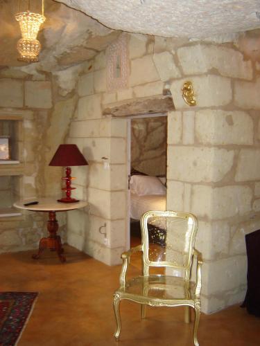 a chair in a room with a bed and a table at Logis Demeure de la Vignole in Turquant