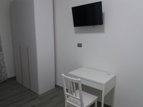 a white desk with a chair and a tv on a wall at Affittacamere Il Borgo in Ceva