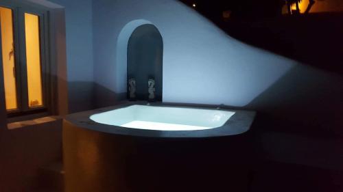 a bath tub with a blue light in a room at The Muses of Santorini Private Jacuzzi Suites in Vóthon