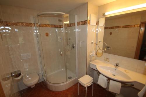 a bathroom with a shower and a sink at Alpenhotel Weiherbach Berchtesgaden Hallenbad und Sauna in Berchtesgaden