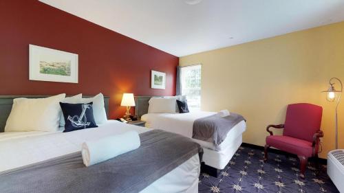 a hotel room with two beds and a red chair at The Inn on Mount Desert in Bar Harbor