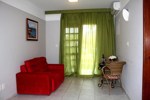 a living room with a red couch and a chair at Chalés Saint Germain in Florianópolis