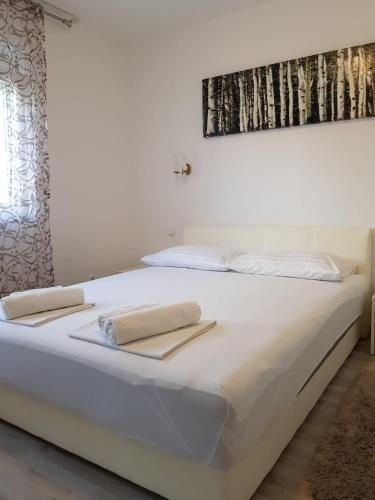 a white bed with two towels on top of it at Apartmani Jureta in Okrug Gornji