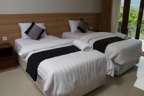 a bedroom with three beds with white sheets at Mandhasativa Homestay in Singaraja