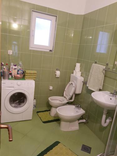 a bathroom with a toilet and a sink and a washing machine at Apartments Maria in Ivanica