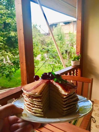 a person holding a plate with a cake on a table at Guest House Kartuli Suli in Tʼelavi