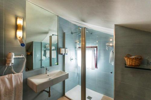 a bathroom with a shower, sink, and mirror at Hotel Bemon Playa in Somo
