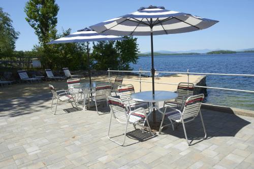 a table and chairs with an umbrella next to the water at Belknap Point Inn in Gilford